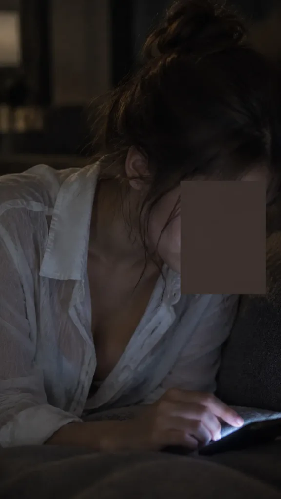 어두운 방 안 스마트폰을 보는 여인