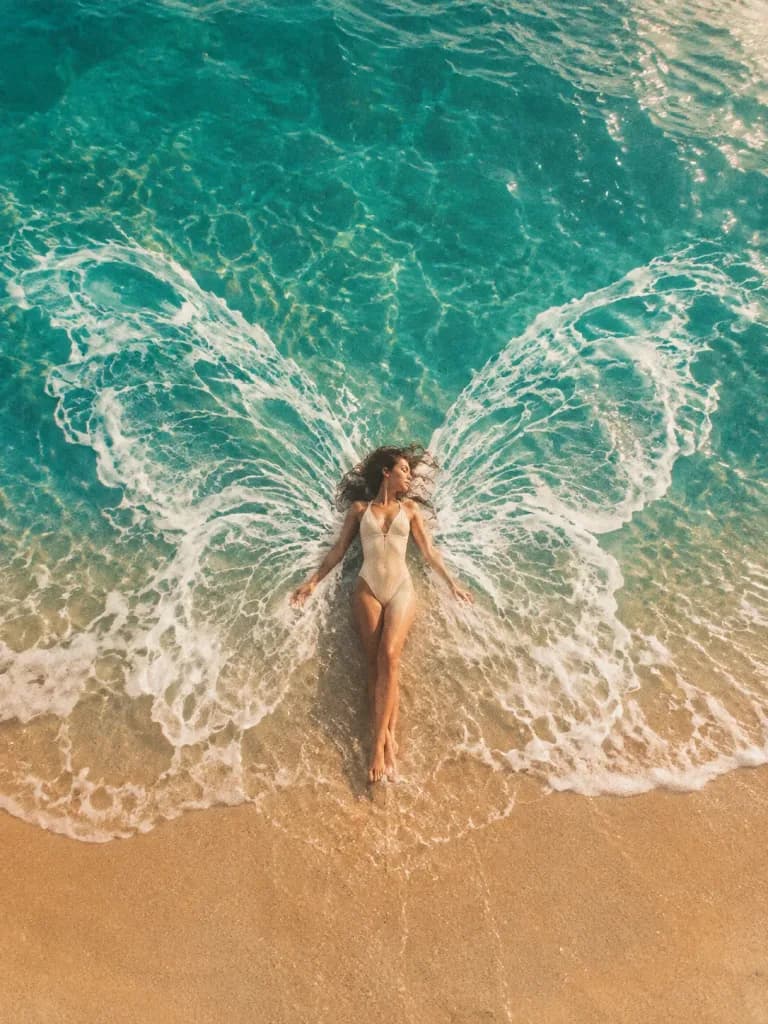 Surreale Frau am Strand mit Schaumflügeln